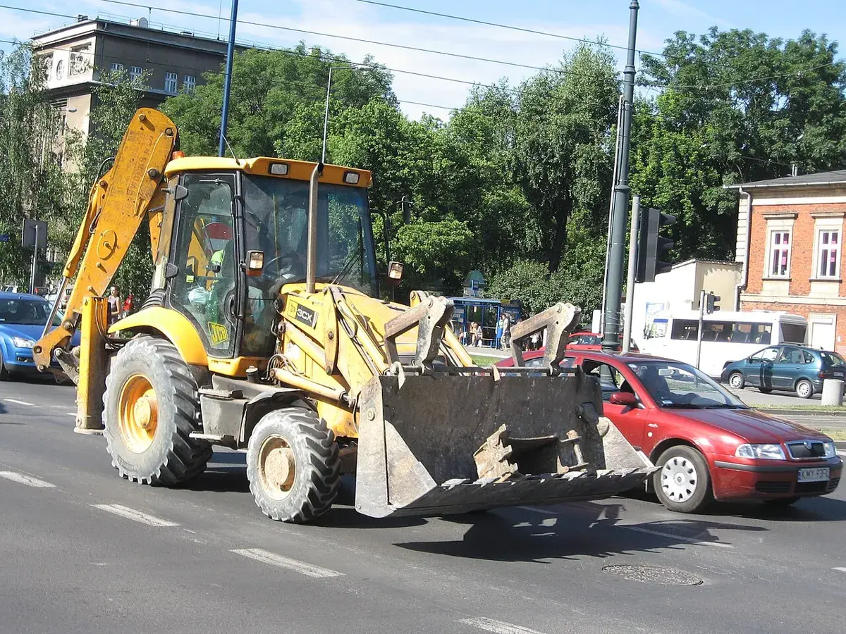 Экскаватор-погрузчик JCB 3CX на городской улице, вид сбоку