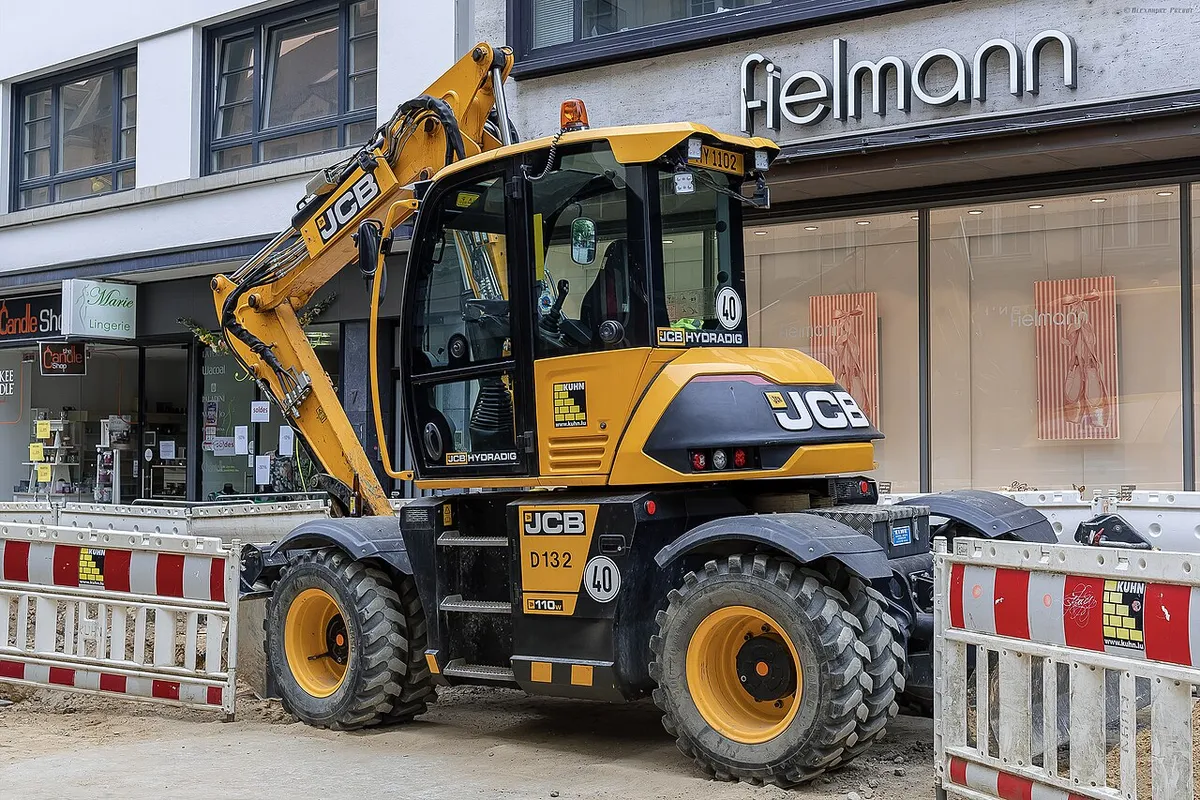 Колёсный экскаватор JCB Hydradig 110W на городской улице за ограждением